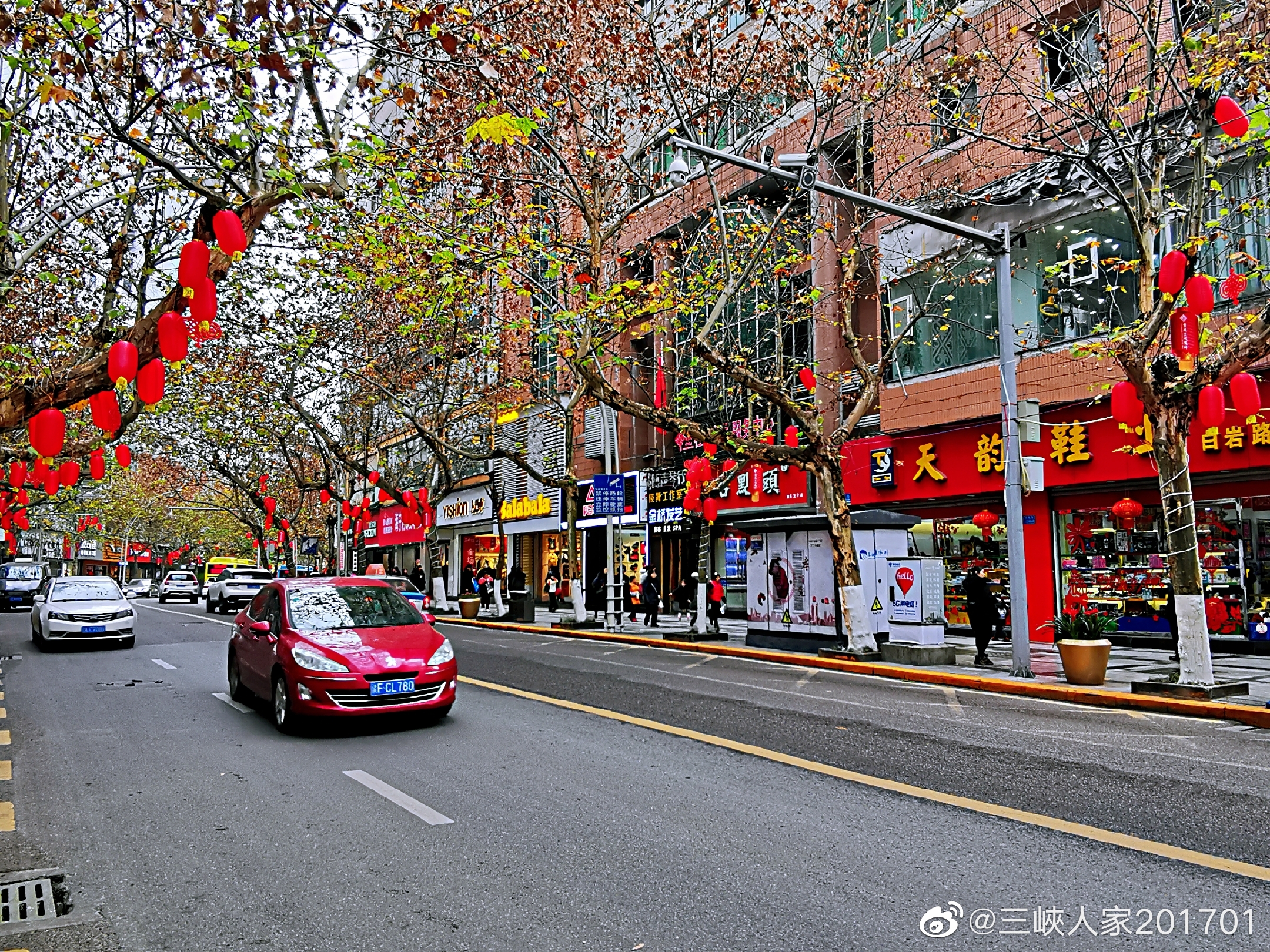 万州区白岩路树上挂着一串串红灯笼,红红的一条街,人行道上白色的,金